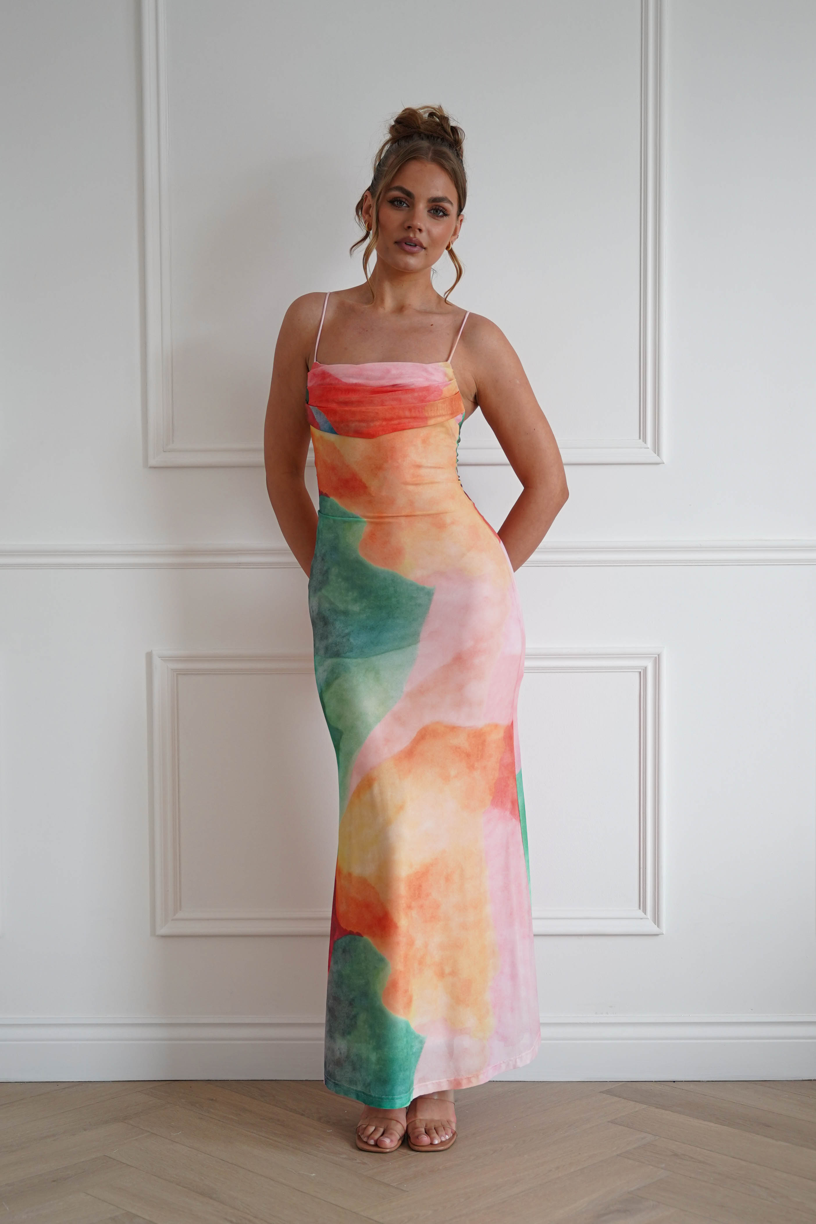 Woman wearing a multicolour abstract print maxi dress with a draped cowl neckline, delicate spaghetti straps, and a fitted floor-length silhouette, perfect for weddings, holidays, summer events, and special occasions.